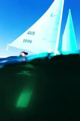 A white-sailed Hansa seen from water level, half above and half below the surface
