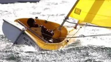 A sailor in a yellow-sailed Hansa on a choppy sea